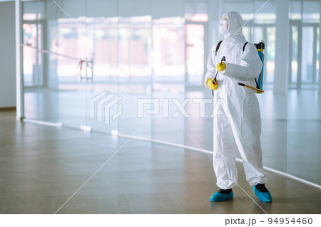 Disinfecting of office to prevent COVID-19, Man in protective hazmat suit with with spray chemicals. 94954460