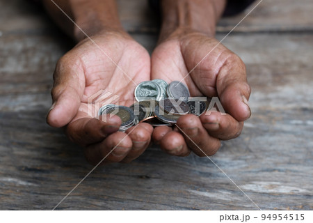 Money, Coins, Grandpa's Pension and Minimal Life Concept - Old Grandpa sadly collects a small coin on a wooden table. 94954515