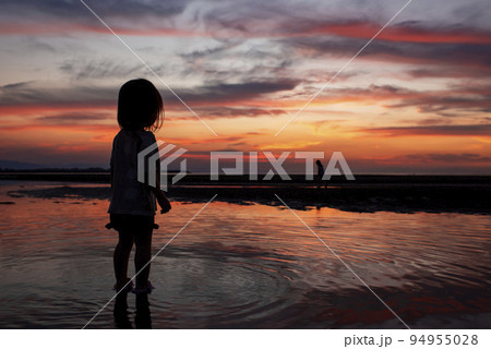 真玉海岸の夕日と海岸で遊ぶ子供のシルエット 94955028