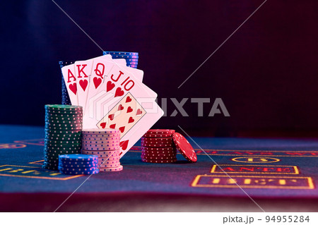 Winning combination in poker standing leaning on multicolored chips piles on blue cover of playing table. Black background. Casino concept. Close-up. Winning combination in poker standing leaning on multicolored chips piles on blue cover of playing table. Black background. Casino concept. Close-up. 94955284