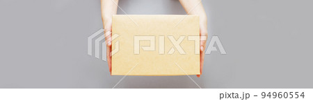 human hands holding delivers carton box on grey background. Delivery and online shopping concept. 94960554