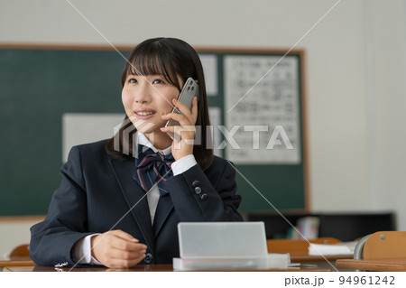 学校の教室でスマホで会話する女子高生 94961242