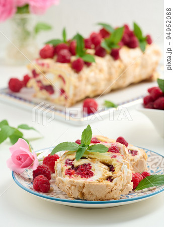 Baked meringue roll with cream and fresh red raspberry, white background 94962088