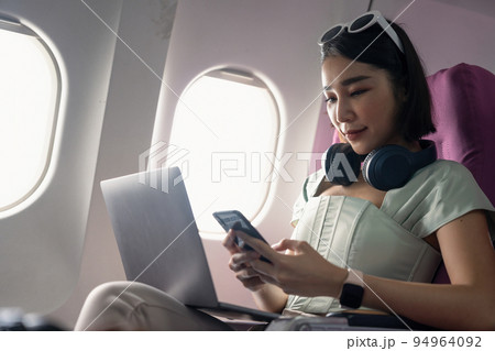 Attractive asian woman passenger of airplane read news from networks via smartphone and wifi on board. tourism traveler concept. Attractive asian woman passenger of airplane read news from networks via smartphone and wifi on board. tourism traveler concept. 94964092