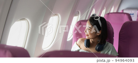 Happy young asian woman on passenger seat near window in airplane. alone travelling concept. Happy young asian woman on passenger seat near window in airplane. alone travelling concept. 94964093