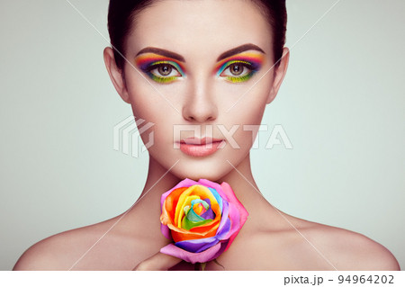 Portrait of beautiful young woman with rainbow rose 94964202