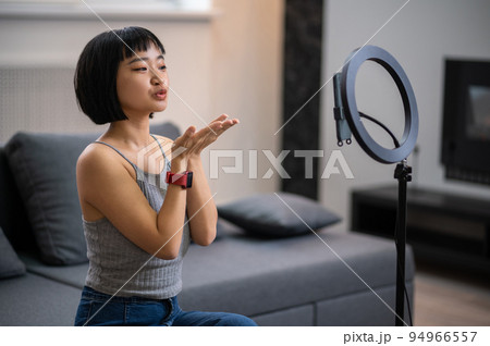 Young Asian video blogger greeting her audience Young Asian video blogger greeting her audience 94966557
