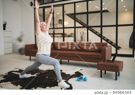 Joyful mature sporty woman working out indoors Joyful mature sporty woman working out indoors 94966564