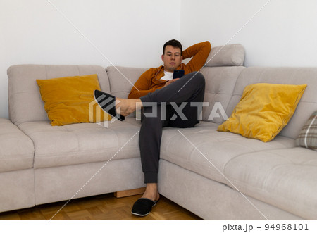 relaxed young man watching mobile phone on couch relaxed young man watching mobile phone on couch 94968101
