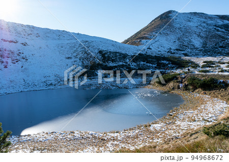 Frozen lake in the mountains. Pond in the mountains. Snow-capped mountains. Landscape with a lake. Frozen lake in the mountains. Pond in the mountains. Snow-capped mountains. Landscape with a lake. 94968672