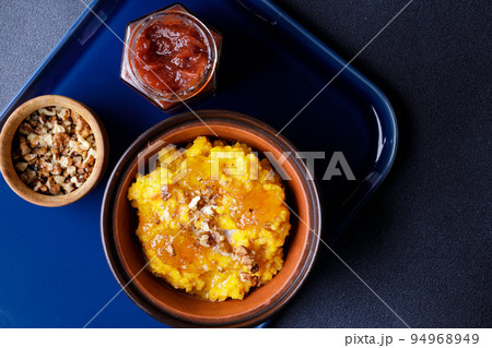 Sweet pumpkin porridge in clay bowl with jam and nuts Sweet pumpkin porridge in clay bowl with jam and nuts 94968949
