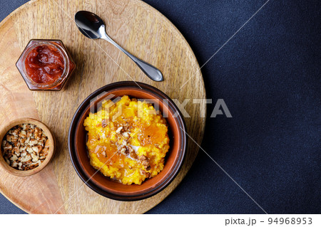 Sweet pumpkin porridge in clay bowl with jam and nuts Sweet pumpkin porridge in clay bowl with jam and nuts 94968953