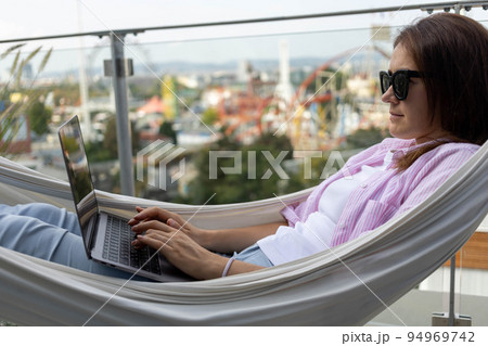 young woman freelancer working in hammock on terrace 94969742