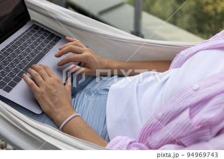 young woman freelancer working in hammock on terrace 94969743