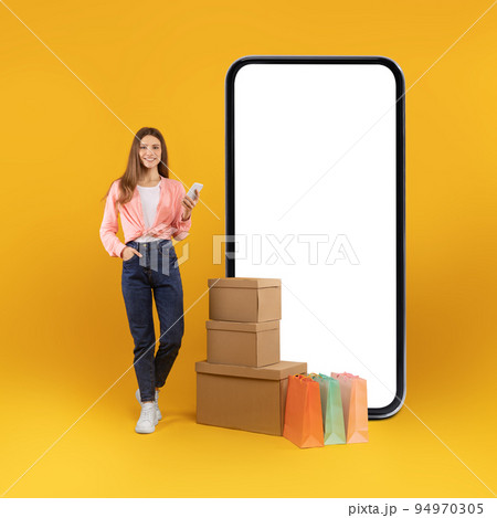 Lady Using Smartphone Near Huge Cellphone Shopping Online, Yellow Background Lady Using Smartphone Near Huge Cellphone Shopping Online, Yellow Background 94970305