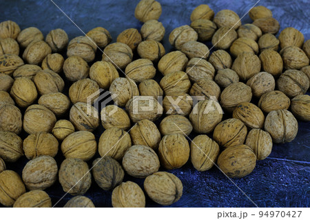 Peeled walnuts. Many closed nuts scattered on a blue background 94970427