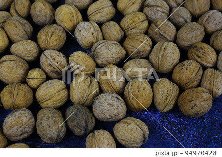 Peeled walnuts. Many closed nuts scattered on a blue background 94970428
