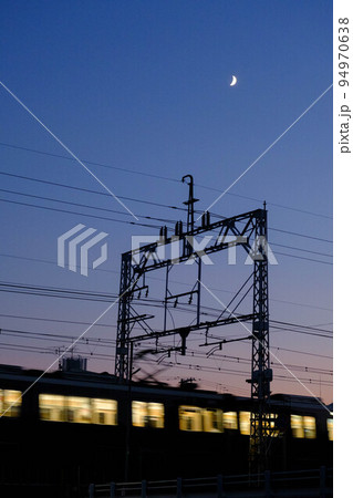 秋の日はつるべ落とし。帰り道急に暗くなり。空には三日月。列車が陸橋を走り抜ける 94970638