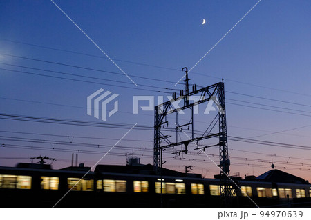 秋の日はつるべ落とし。帰り道急に暗くなり。空には三日月。列車が陸橋を走り抜ける 94970639