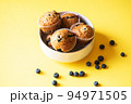 Blueberry muffins served in a bowl on a yellow background. Overhead view. 94971505