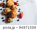 Blueberry and strawberry muffins with berries on a marble background. Close up and copy space. 94971509