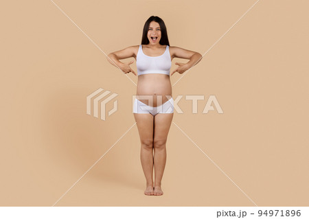 Maternity Concept. Cheerful Pregnant Woman In Underwear Pointing At Her Belly 94971896