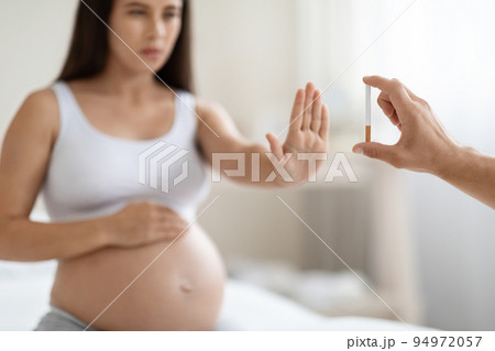 Pregnant woman showing stop gesture to cigarette Pregnant woman showing stop gesture to cigarette 94972057