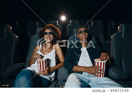 Couple watching movie with popcorn in cinema. Couple watching movie with popcorn in cinema. 94972549