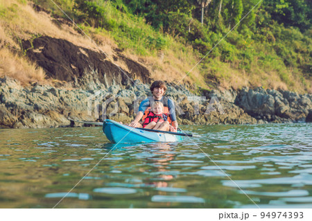 Father and son kayaking at tropical ocean. Father and son kayaking at tropical ocean. 94974393