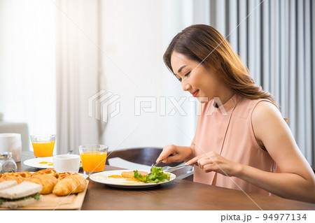 Asian young woman sitting kitchen table food having eating healthy breakfast at home 94977134