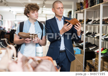 Man and teenager looking for classic shoes in shoe store 94977395