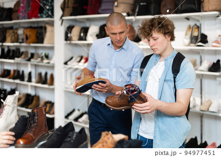 Man and teenage boy choosing demi-season shoes in store Man and teenage boy choosing demi-season shoes in store 94977451