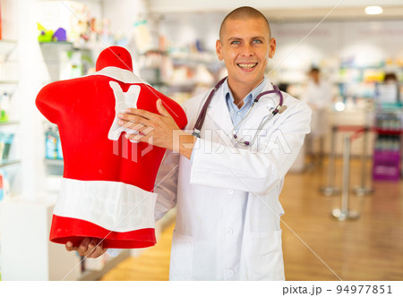 Positive pharmacist or doctor offers an orthopedic patch for the back. Demonstration of the work plaster on mannequin Positive pharmacist or doctor offers an orthopedic patch for the back. Demonstration of the work plaster on mannequin 94977851