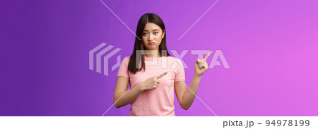 Moody upset whining girlfriend unhappy pointing left, sulking look miserable and distressed, express regret and disappointment, complain bad fortune, stand purple background displeased 94978199