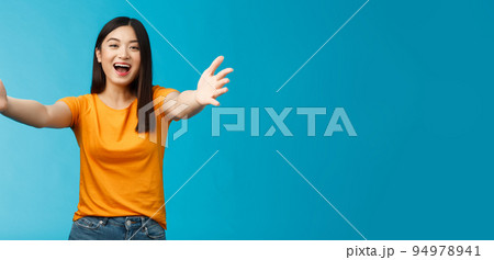 Come closer let me hug you. Cheerful lovely asian brunette girl stretch hands forward wanna cuddle, embracing friend smiling broadly inviting dear guests welcoming, stand blue background Come closer let me hug you. Cheerful lovely asian brunette girl stretch hands forward wanna cuddle, embracing friend smiling broadly inviting dear guests welcoming, stand blue background 94978941