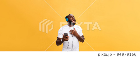 African American man with headphones listen and dance with music. Isolated on yellow background 94979166