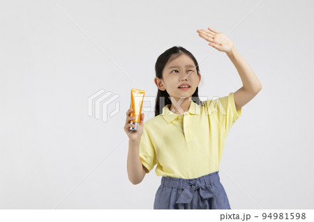 Korean young girl wearing gym clothes in white background studio__dazzling in the sun, holding a sun cream 94981598