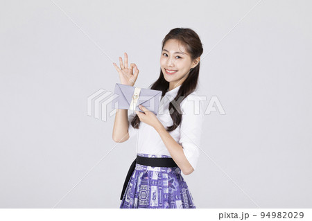 beautiful Korean woman in 20s wearing modern Hanbok_holding a Korean traditional wedding clutch, envelope with ok sign motion 94982029