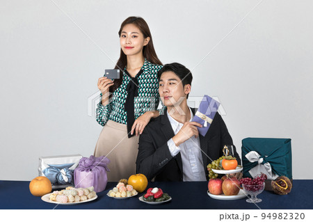 Korean young couple, man and woman wearing modern Hanbok_holding credit card and Korean traditional wedding clutch, envelope 94982320