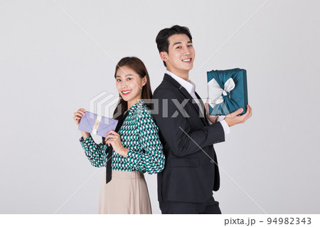 Korean young couple, man and woman wearing modern Hanbok holding gift box and Korean traditional wedding clutch, envelope Korean young couple, man and woman wearing modern Hanbok holding gift box and Korean traditional wedding clutch, envelope 94982343