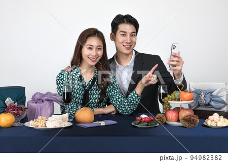 Korean young couple, man and woman wearing modern Hanbok_watching smartphone Korean young couple, man and woman wearing modern Hanbok_watching smartphone 94982382
