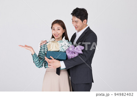 Korean young couple, man and woman wearing modern Hanbok_holding gift box Korean young couple, man and woman wearing modern Hanbok_holding gift box 94982402