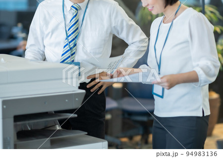プリントした書類で立ち話する男女 94983136