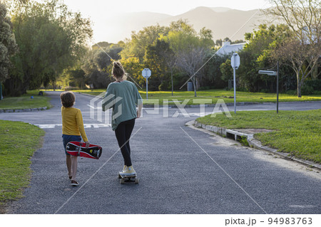 Brother (8-9) and sister (16-17) skateboarding Brother (8-9) and sister (16-17) skateboarding 94983763