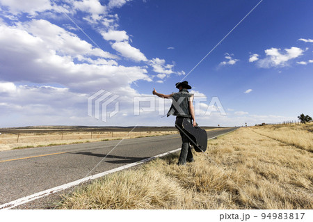 Usa, New Mexico, Hitchhiker on desert road 94983817