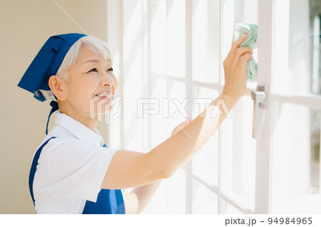 窓拭きをするハウスキーパーのシニア女性 94984965