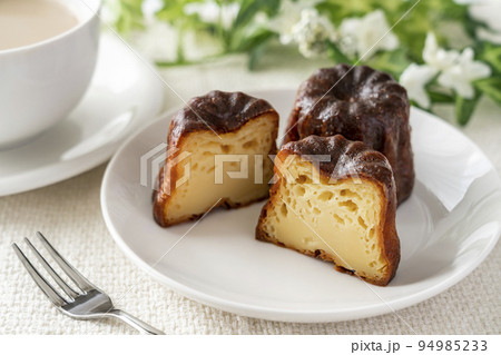白いお皿にのったフランスの洋菓子カヌレとカフェラテ 白いお皿にのったフランスの洋菓子カヌレとカフェラテ 94985233