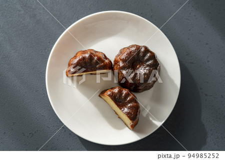 白いお皿にのったフランスの洋菓子カヌレ【黒背景】 94985252