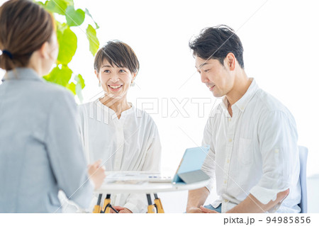 スーツ姿の女性から説明を受ける夫婦 スーツ姿の女性から説明を受ける夫婦 94985856