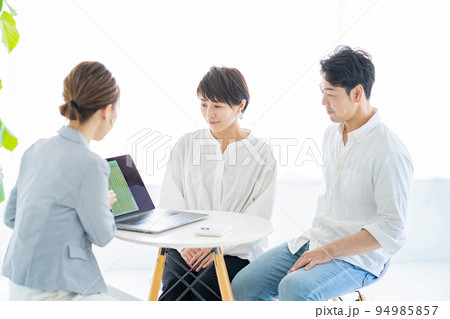 スーツ姿の女性から説明を受ける夫婦 スーツ姿の女性から説明を受ける夫婦 94985857